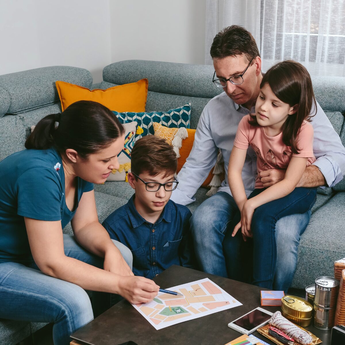 Family gathered around a table at home, discussing and writing down an emergency plan together.